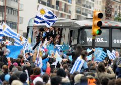 The bus with the team surrounded by a joyous crowd draped in flags