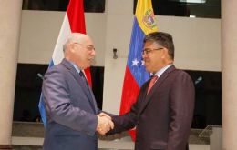 The two ministers with the background of the two flags shake hands in Asunción 