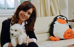 Cristina Fernandez holding the pup Simon, a gift from Hugo Chavez brother Adan and next to a giant penguin sent by a well wisher 