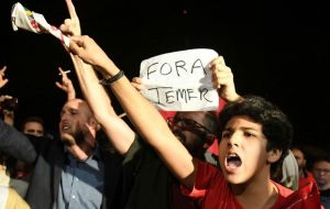 Local media, including Globo news, captured video images of military police firing pistols into the air. Protestors carried signs calling for “Out with Temer”
