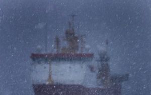 Ice Patrol HMS Protector in Antarctica under heavy snow and surrounded with penguins at Port Lockroy 