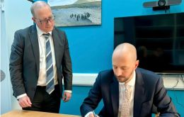 Deputy Director for Overseas Territories Directorate, Adam Pile OBE, signs the documents at Falklands Government House