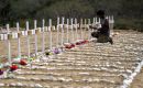 A worker paints the graves of unidentified victims of the June 24 earthquake. Photo: Miguel Medina / AFP