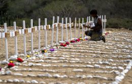 A worker paints the graves of unidentified victims of the June 24 earthquake. Photo: Miguel Medina / AFP