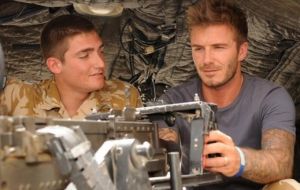 David Beckham being shown the mounted heavy machine gun on an Army Lynx helicopter