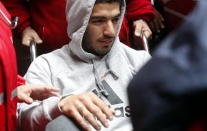 Suarez in a wheelchair is taken from the ambulance to his home