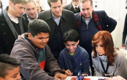 The Argentine president at the Villa 20 township school watching children manipulate car model robots    