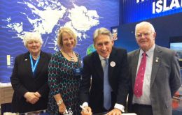 The Foreign Secretary signing the visitors' book at the Falklands stand next to FIGO representative Sukey Cameron and MLAs Jan Cheek and Roger Edwards 