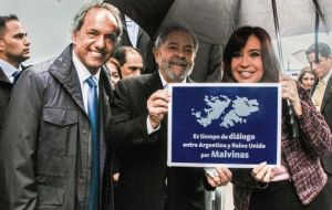 Lula da Silva next to Cristina Fernandez and presidential hopeful Daniel Scioli share a picture with the sign