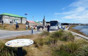 A tour bus stops at the Liberation Monument in Stanley for visitors to take pictures  