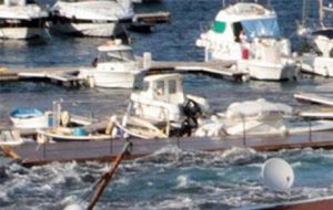 As water starts to foam behind the cruise ship, a thick wake surges towards the shore instantly smashing through the concrete pier and tumbling docked boats