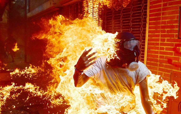 In a dramatic scene caught by a photographer, a protestor was severely burned when the gas tank of a police motorcycle exploded during clashes 