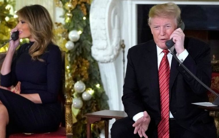 Donald Trump and his wife Melania were taking calls from American children as the couple sat under two gargantuan Christmas trees