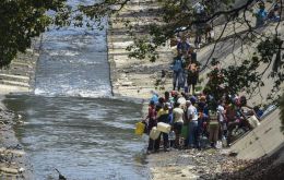 Dozens of people flocked to the Guaire river, which snakes along the bottom of a sharp ravine alongside Caracas' main highway, to fill up a 15-litre plastic container
