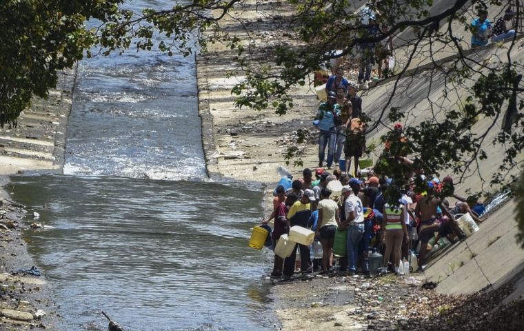 Dozens of people flocked to the Guaire river, which snakes along the bottom of a sharp ravine alongside Caracas' main highway, to fill up a 15-litre plastic container