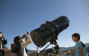 A spectator looking at the sun and moon through a telescope that is equipped with the proper solar filter for safe viewing. 