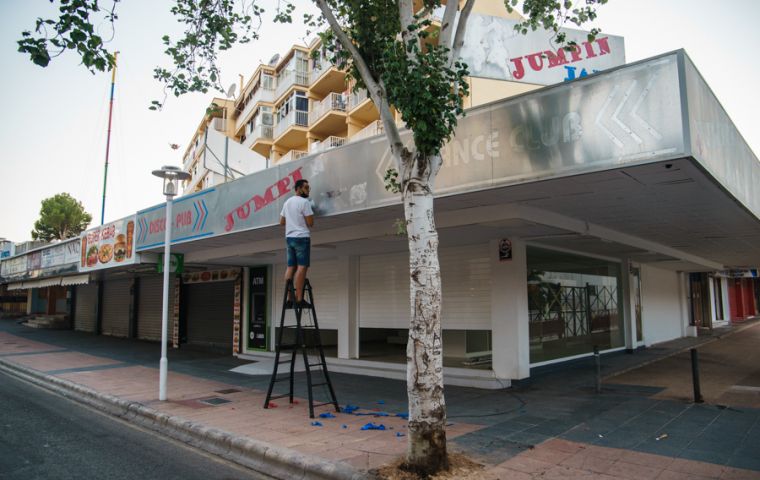 A man works last Thursday on the front of a recently closed bar in the major holiday resort of Magaluf in Mallorca Island. SEBASTIÁN ASTORGA