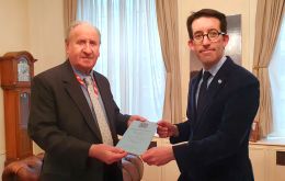 Lord Lee of Trafford hands the copy at the Falklands' Government Office in London to representative Richard Hyslop