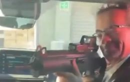 In the video, diplomat Jon Benjamin appears in the front seat of a vehicle and points the weapon towards staff seated at the back